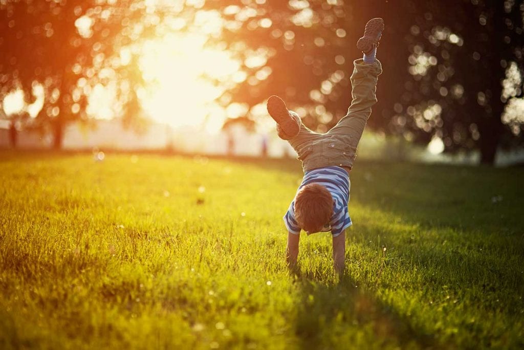 young boy doing handstand outside on grass