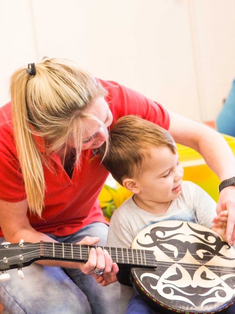 woman helping young boy play a musical instrument